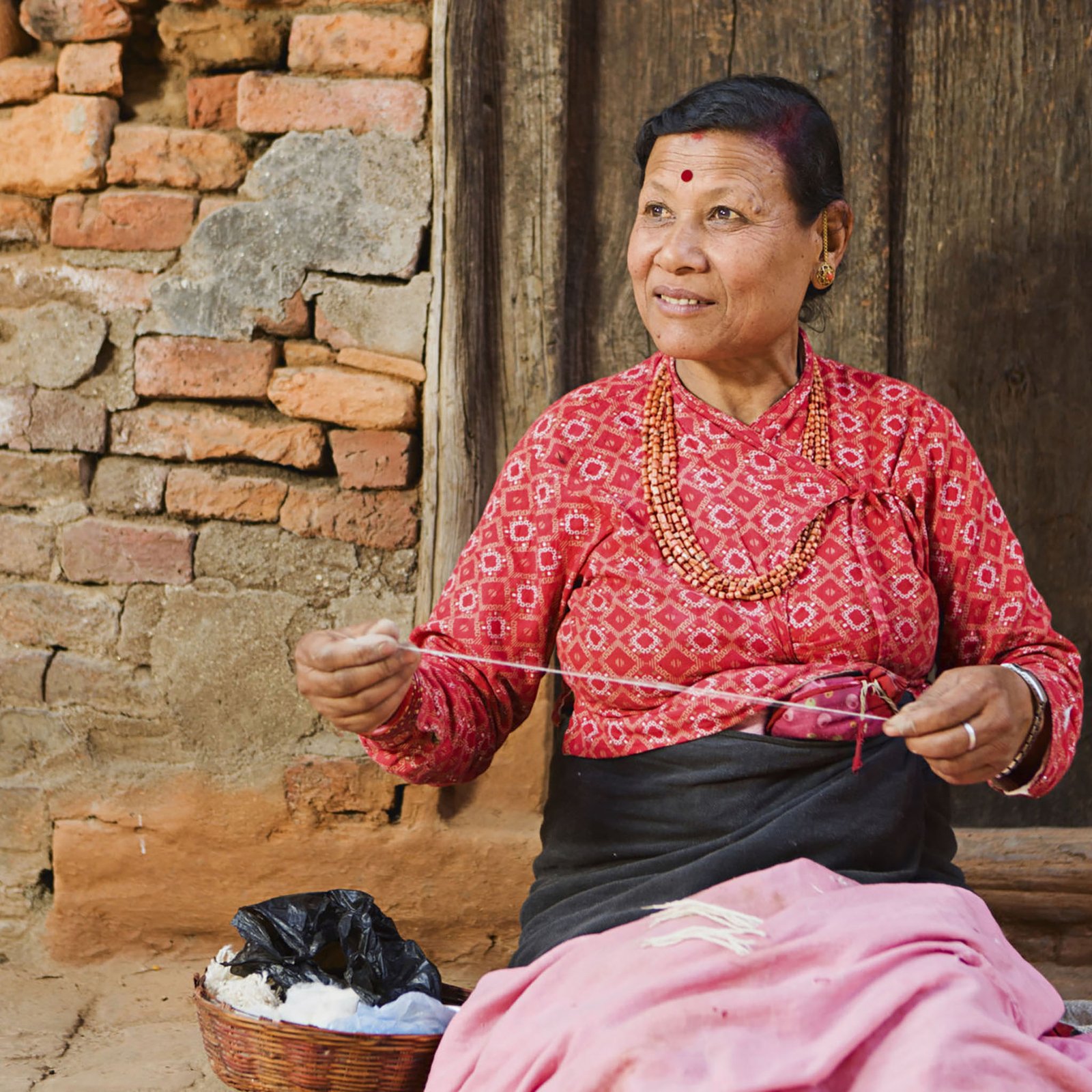 Nepali woman using spinning machine to make a wool. Bhaktapur. Kathmandu valley. Nepal.http://bem.2be.pl/IS/nepal_380.jpg